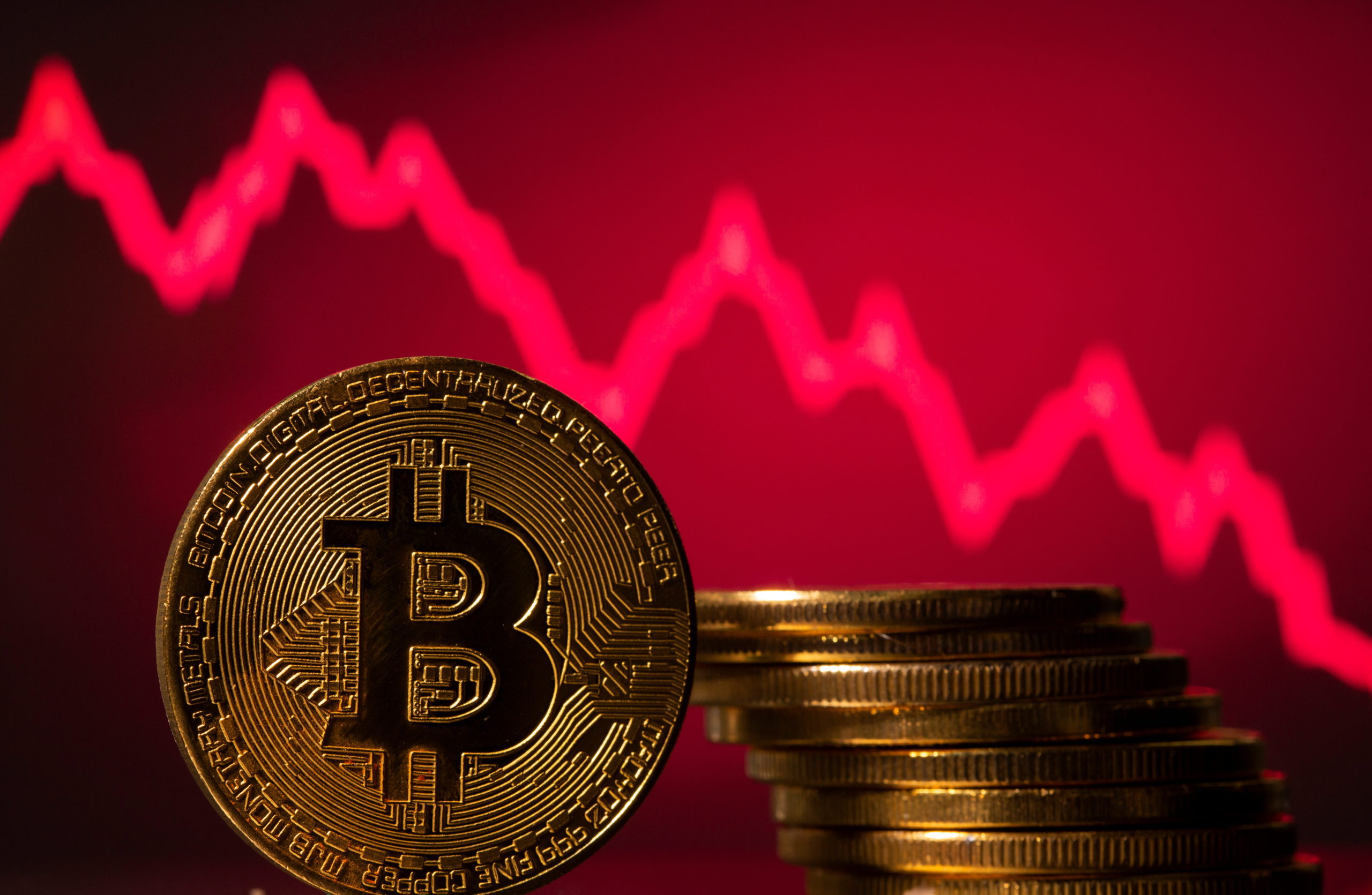 A representations of virtual currency Bitcoin is seen in front of a stock graph in this illustration